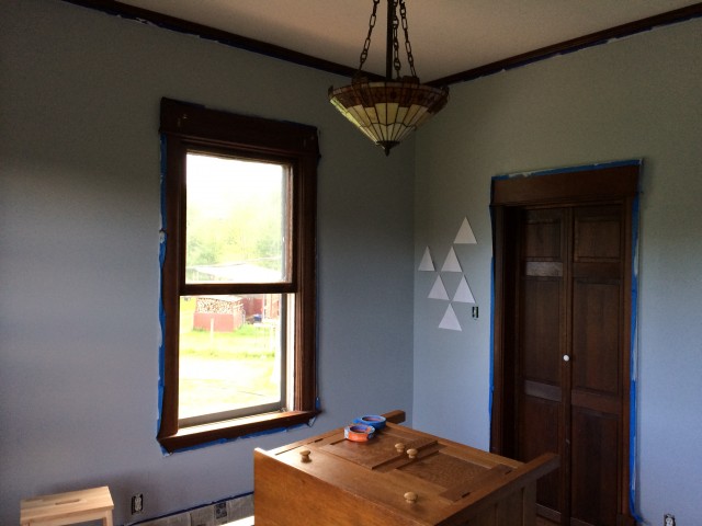 The nursery was a weird teal color, until our painting team (Alicia, Mimi and Josie) primed it and put on two coats of a light grey. We're working on a stencil to add multi-colored triangles on two walls.
